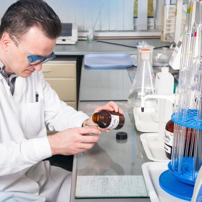 Laboratory assistant pours liquid from a bottle with sodium oxalate